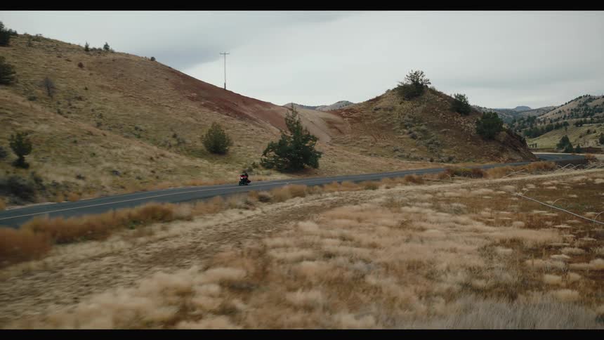A motorcycle is riding down a road through the mountains