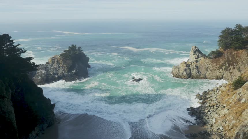Heavy waves crash against the shoreline below