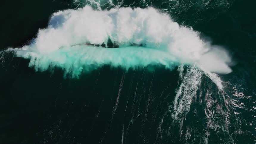 Aerial views capture the dramatic movement of ocean waves crashing and spreading white foam across the dark blue sea
