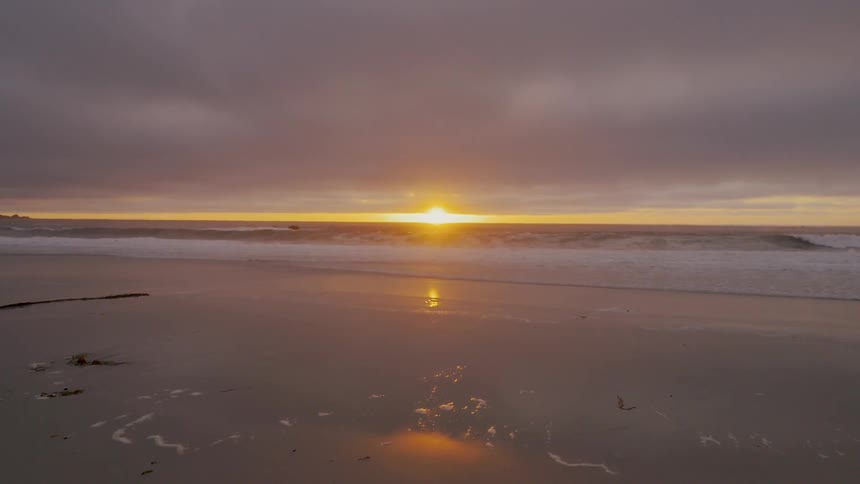 The sunset on a beach with the water coming in slowly