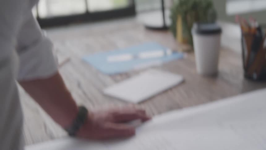 Man stands and writes on a large pad in his office during the day