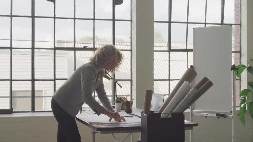 A woman is looking at blueprints on her desk