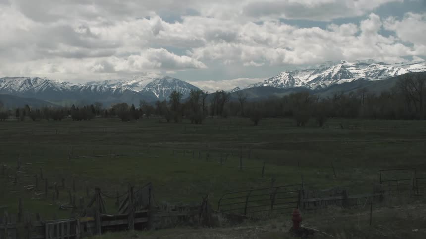 View of a pasture and mountains on a cloudy day