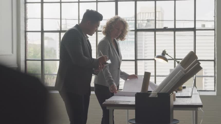 A footage of a man and a woman reading a document in the office