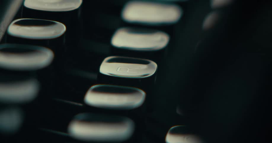 Closeup of fingers typing on the keyboard of a vintage typewriter