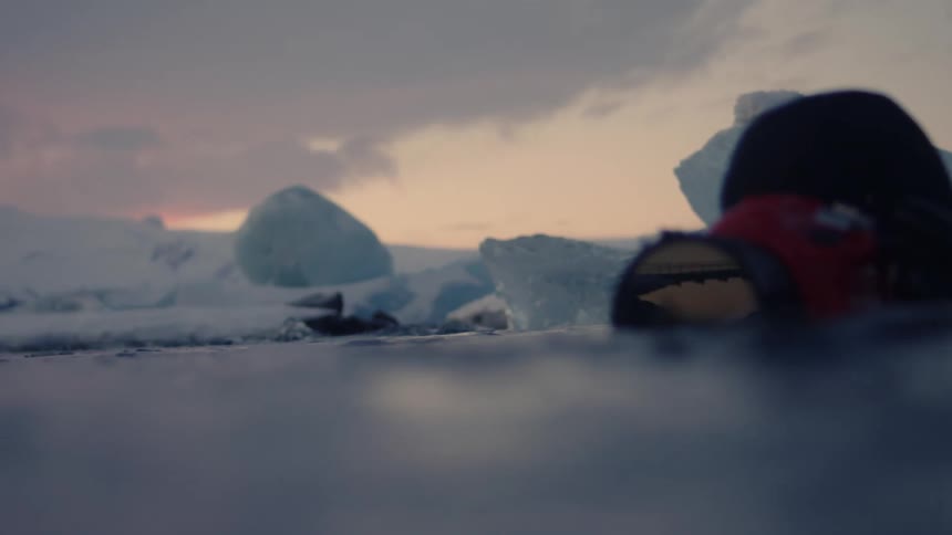 A man floats in the water with his camera at the surface photographing