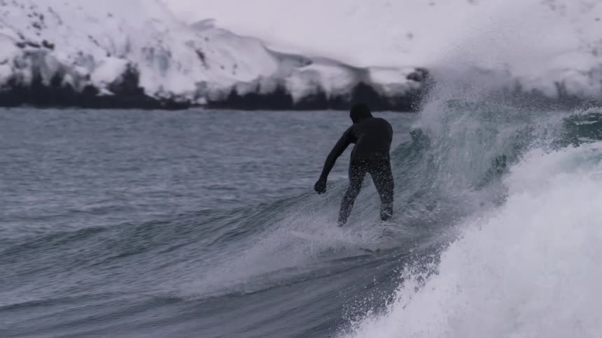 A man is surfing in the winter
