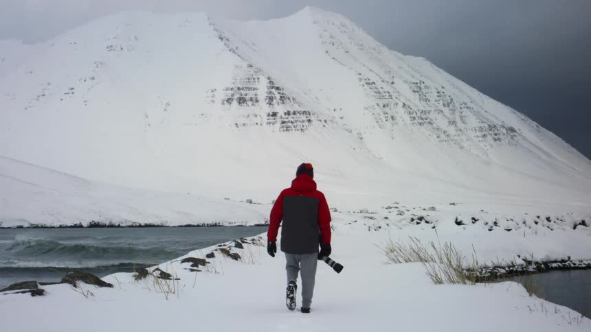 A man walks in the snow towards the mountain
