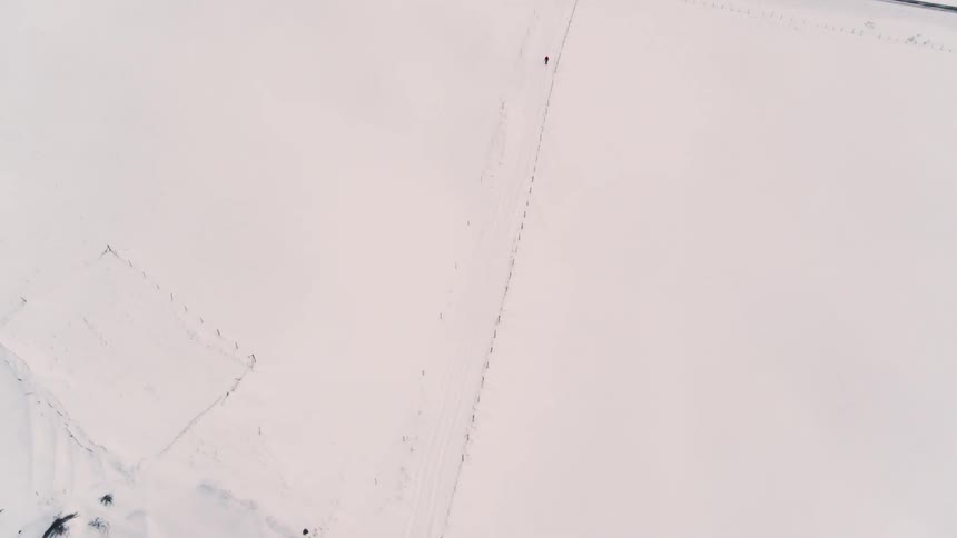 An aerial footage of a person walking in the snow