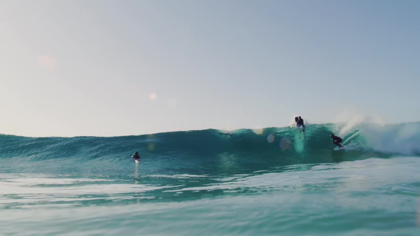 People are surfing a large wave in the ocean