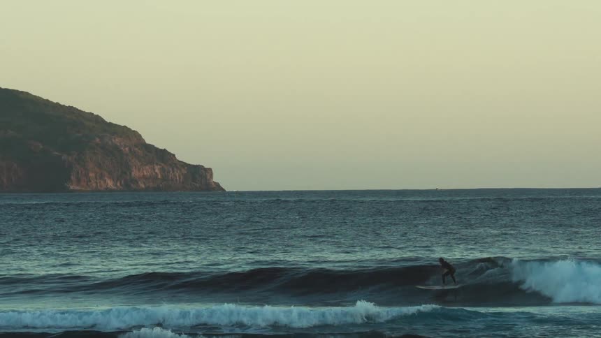 A man rides a wave on his surfboard towards the shore