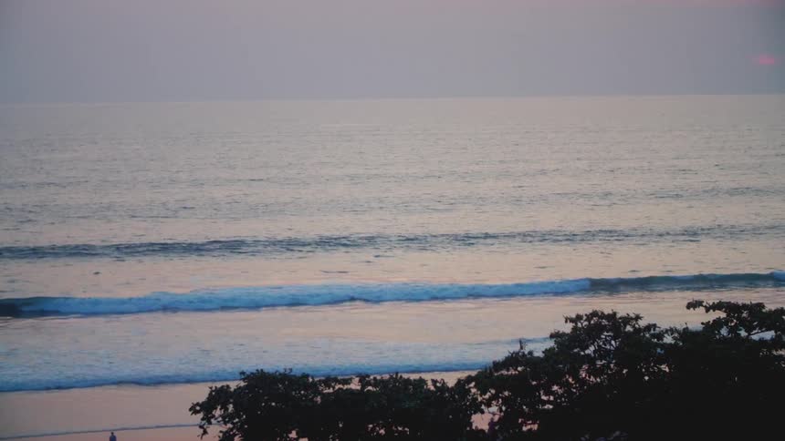 Small waves gently rolling into the shoreline at dawn