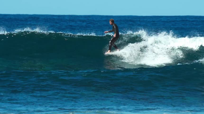 A man surfs a wave on a sunny day