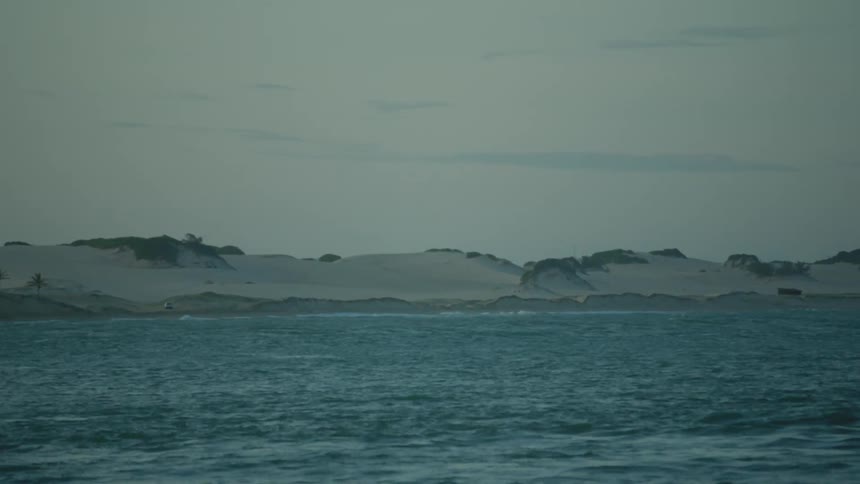 A landscape shot of the ocean near a snowy tundra shore