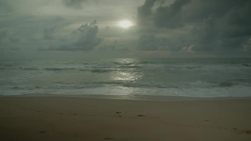 Sunset reflecting off the ocean as tide gently rolls onto sandy shoreline