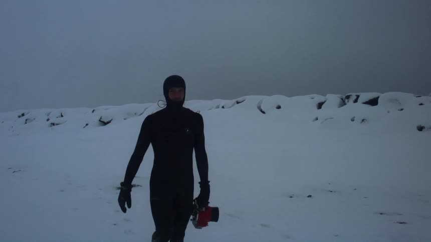 A man is carrying a large camera in the snow