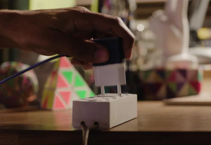 Plugging in a charging cord with an adapter into a mounted outlet on a table