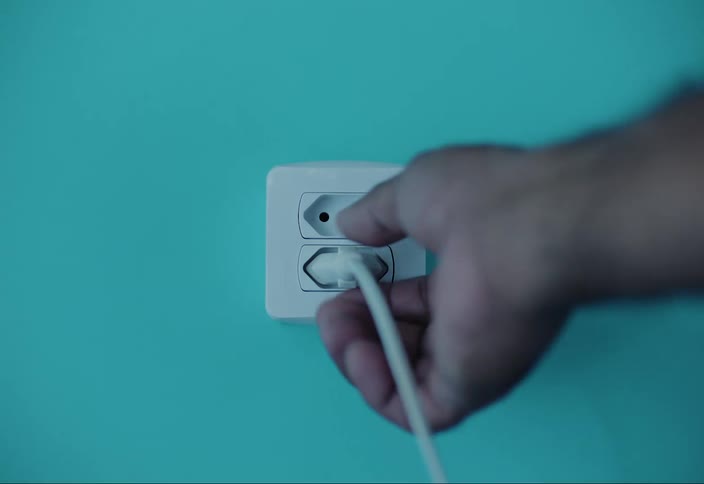 Person removes a plug from the outlet with three holes arranged in an upside down v shape