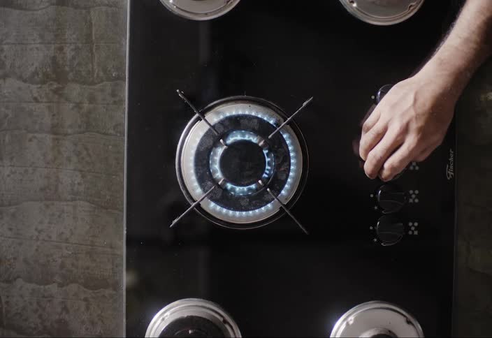 A man turns the switch on the stove top