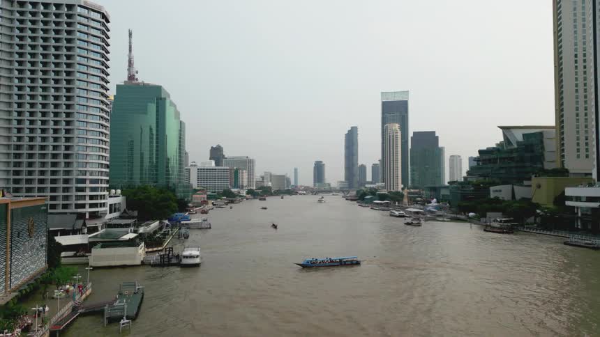 A river flowing through a modern cityscape with boats navigating the water and skyscrapers lining both banks