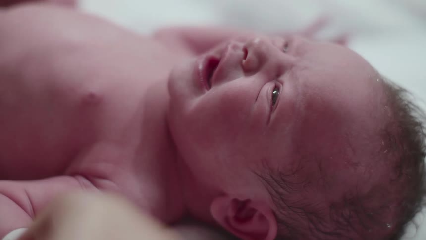 Newly born baby crying while having diaper put on