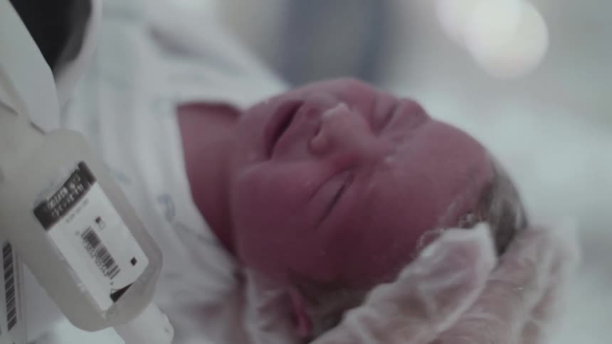 Newly born infant crying while having their head washed by nurse in the hospital