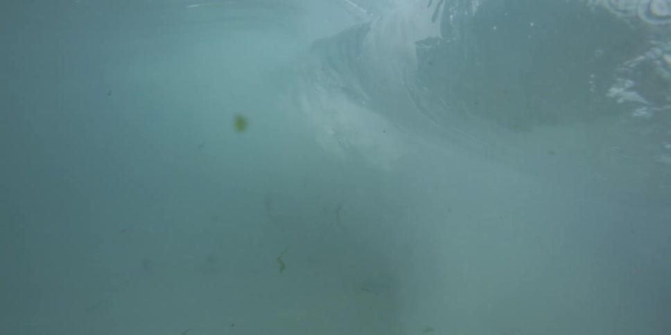 Wave rolls and crashes sending bubbles through the water