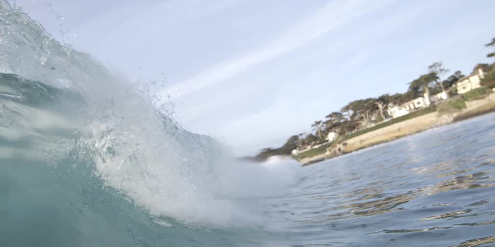 Large wave crashes as it nears the beach and the residential building located nearby