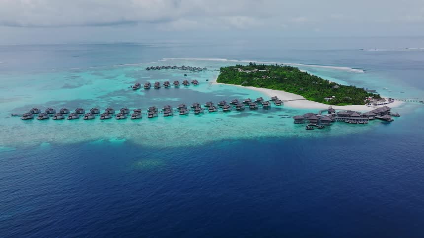 Remote travel destation aerial of tropical island with white sand beach and over the water bungalows