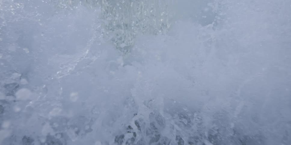 A powerful wave breaking its white foam contrasting with the dark churning water under an overcast sky