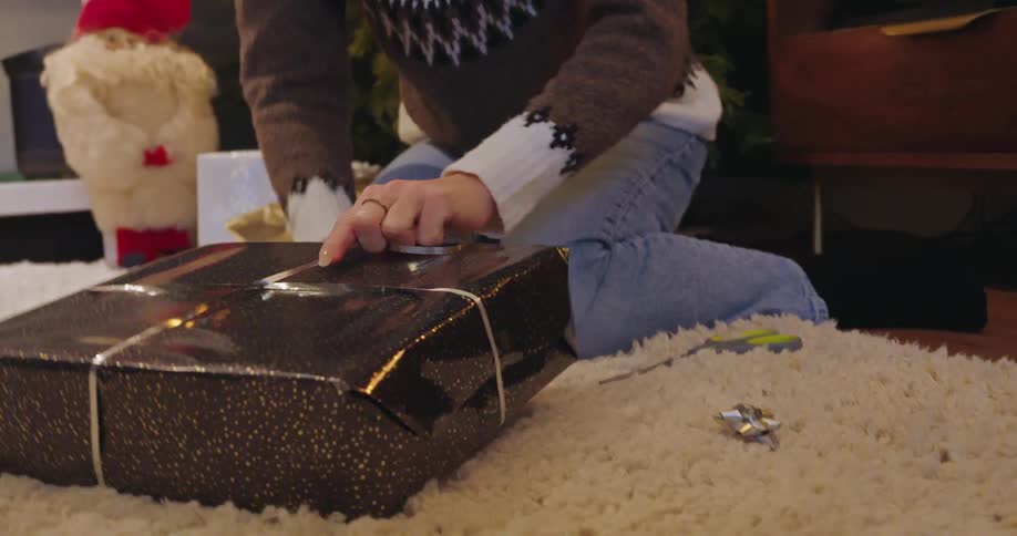 A woman uses silver string to wrap a present