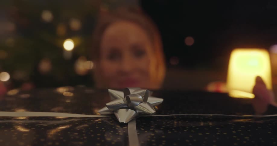 A big wrapped gift is handed to a woman on christmas