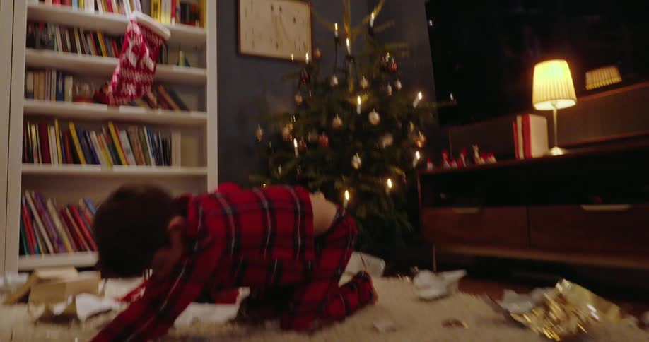 A child is throwing wrapping paper in the living room