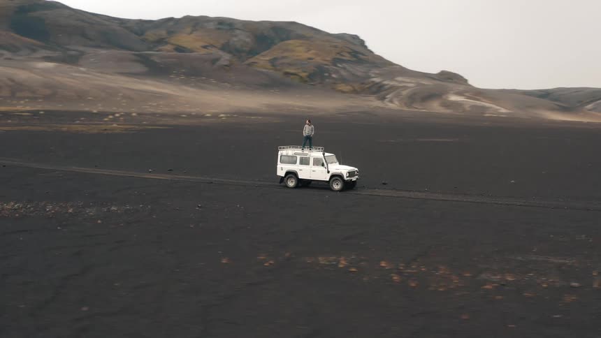 A man is standing on top of his vehicles in the landscape