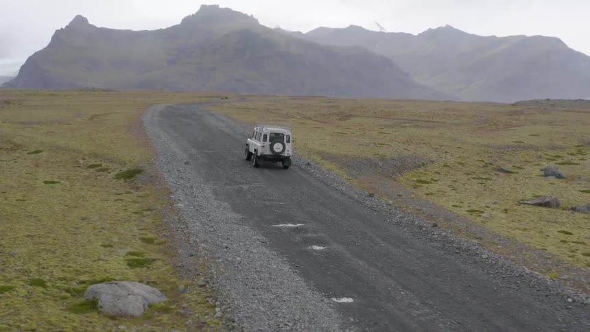 The vehicle drives on a trail off road towards a mountain