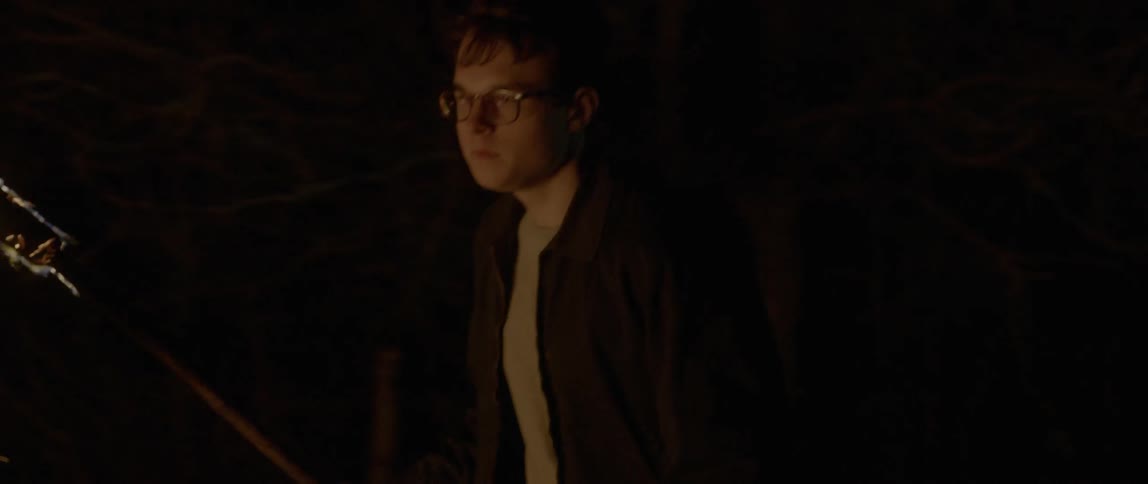 A man running with a stick in his hand near a fire while it is night time