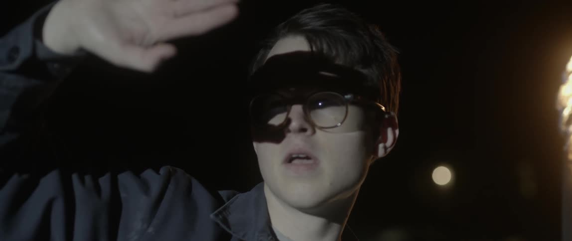 A man shades his eyes from a bright light at night