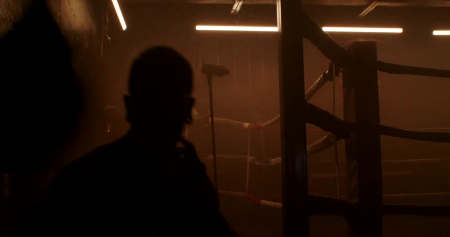 A man is in a dark gym punching a speed bag
