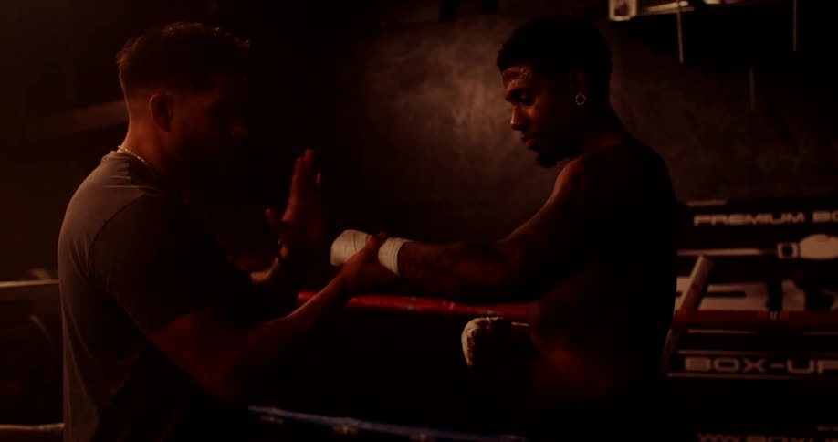 A couch tightens the tape on the boxers hands