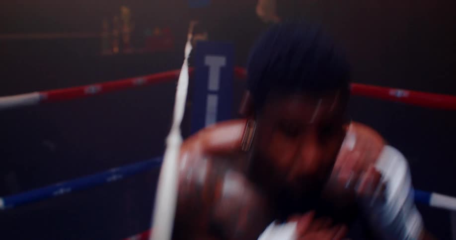 A boxer in gloves practices slipping under a taut string in the ring moving left and right to refine evasive techniques