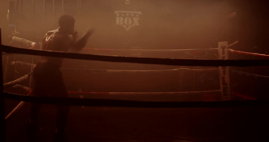 A male boxer is practicing his skills in an empty gym