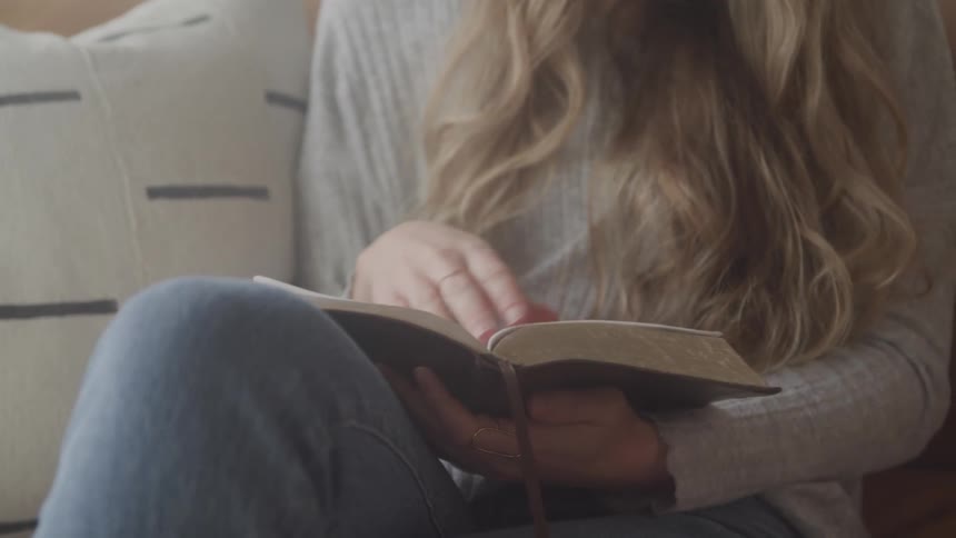 A woman is reading a book while sitting