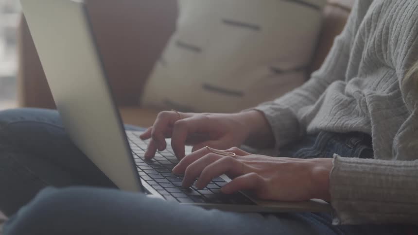 Female sitting on couch typing on laptop