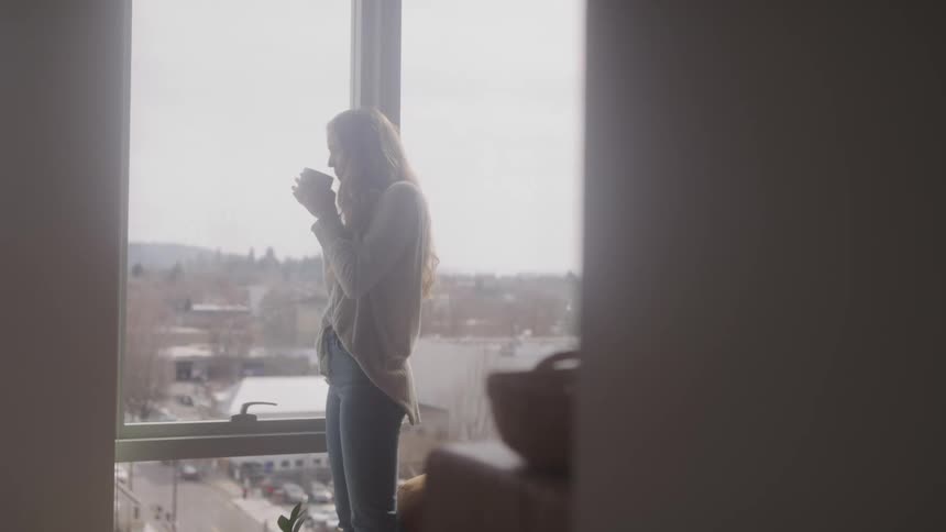 A footage of a lady dinking close to the window
