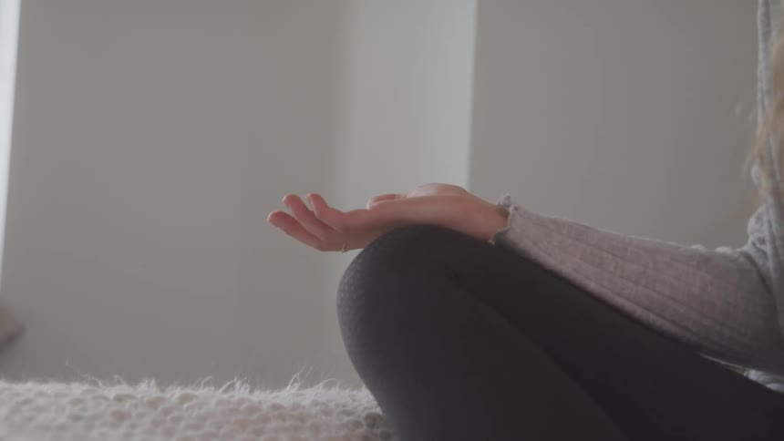 A woman is doing a yoga pose while sitting indoors