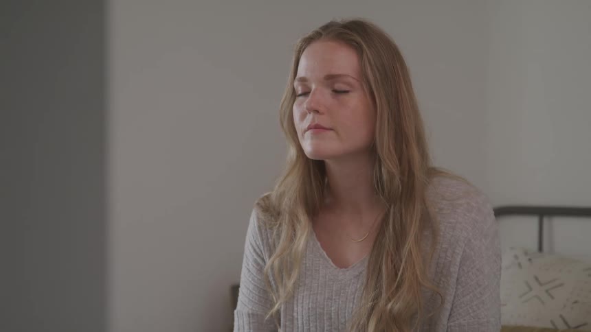 Girl with closed eyes sitting in a bed in a room