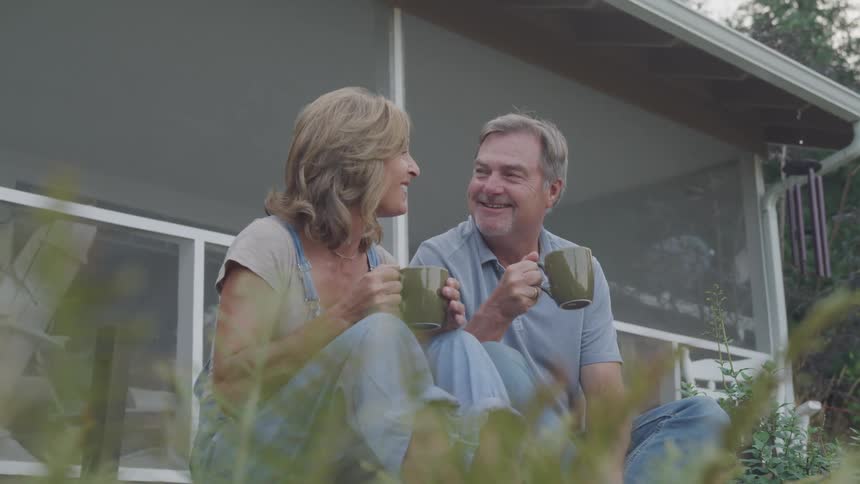 A couple drink coffee in their garden