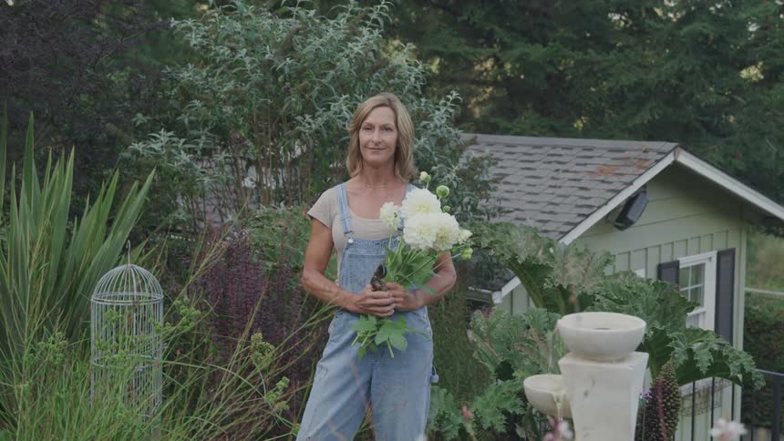 Woman holding a bouquet of white flowers standing in her garden