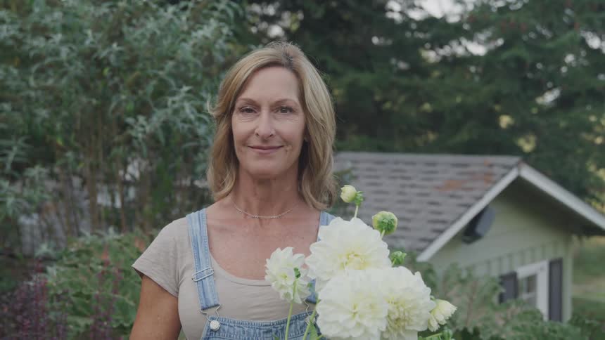 A woman is holding flowers outside