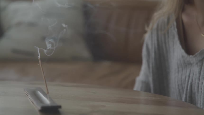 A woman is lighting incense at home